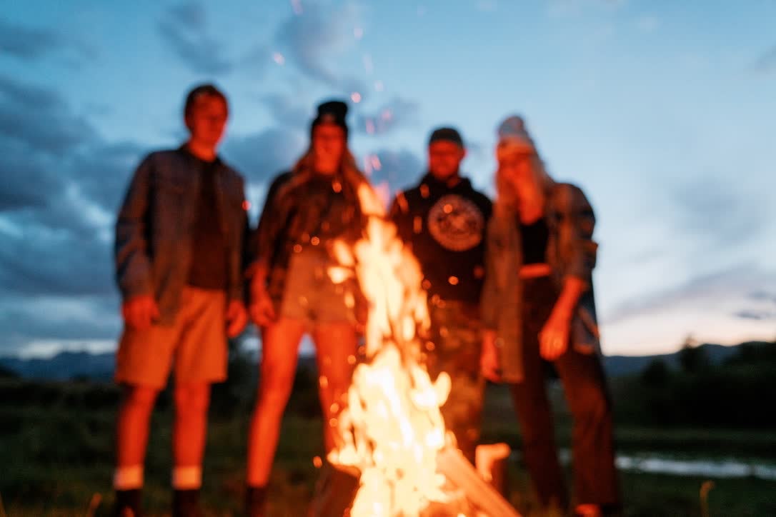 People gathered around a warm campfire at dusk