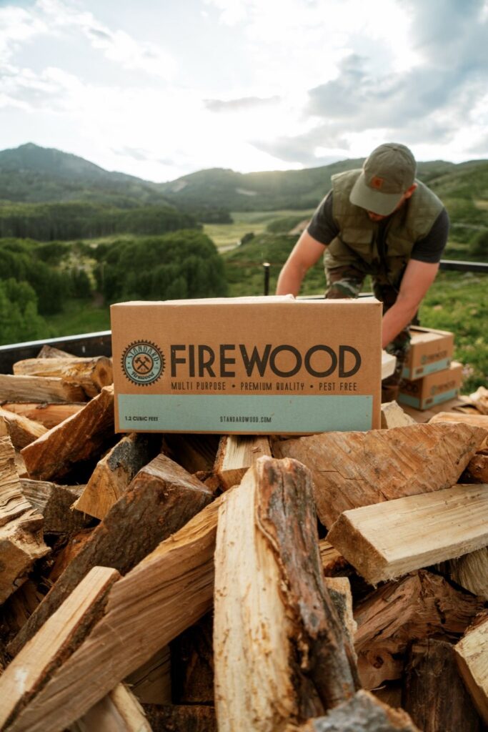 Standard Firewood box on a pile of split firewood near Park City, Utah, with a worker and more boxes behind