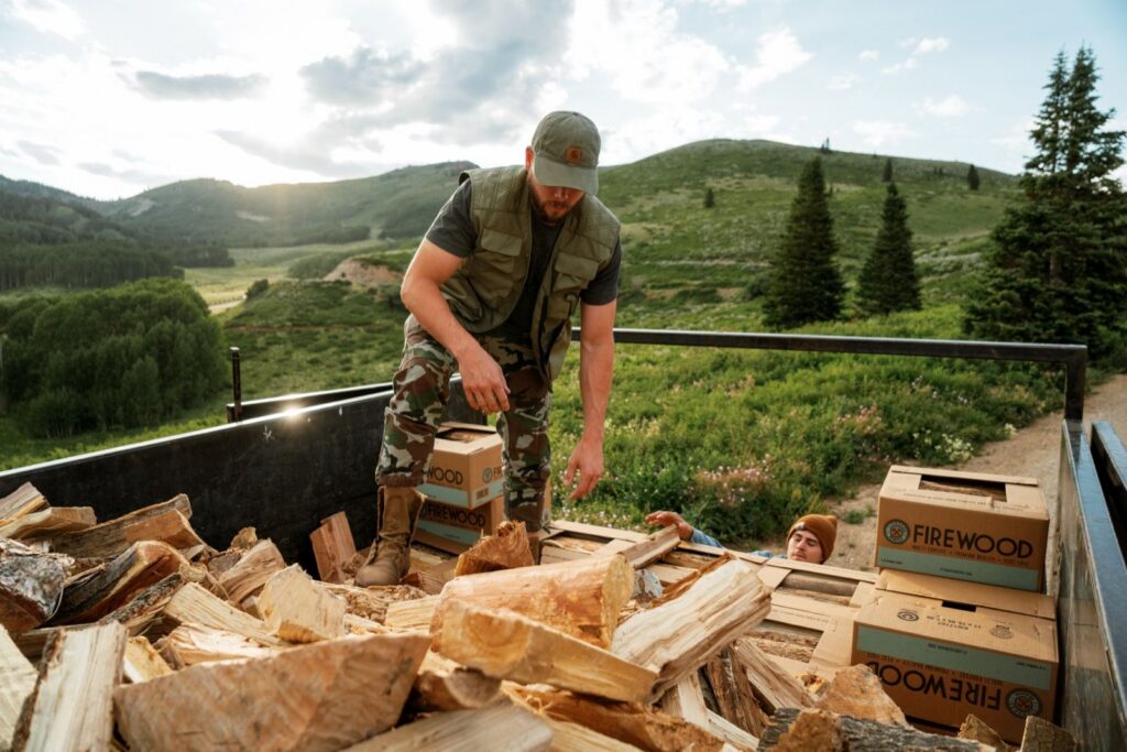 Worker in a trailer loaded with split firewood and Standard Firewood boxes in the mountains near Park City, Utah